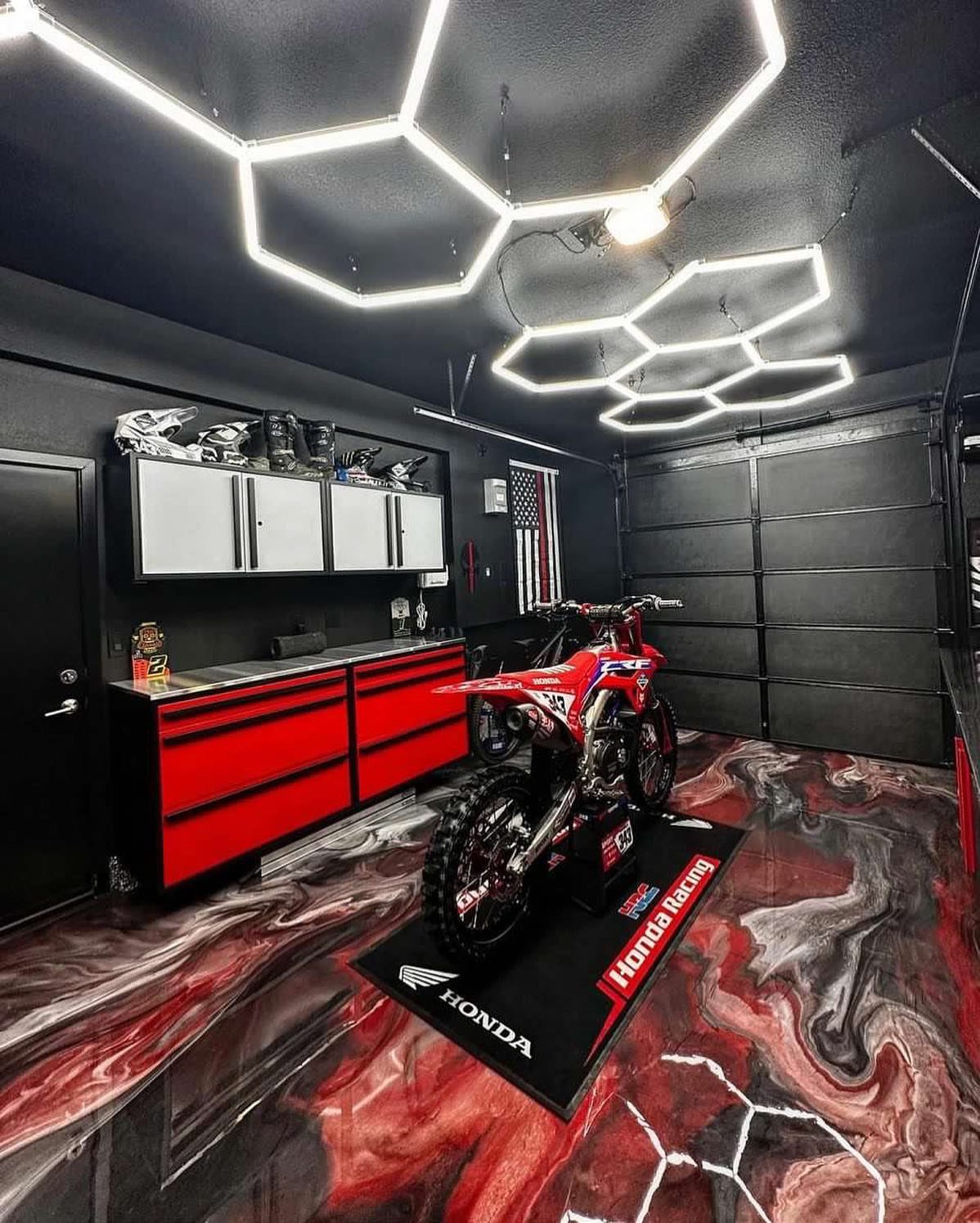 Garage Tool Setup: 8 Ideas That Actually Save Space and Time 2 Hexagonal LED light fixtures illuminating a modern garage with red tool cabinets and a dirt bike.