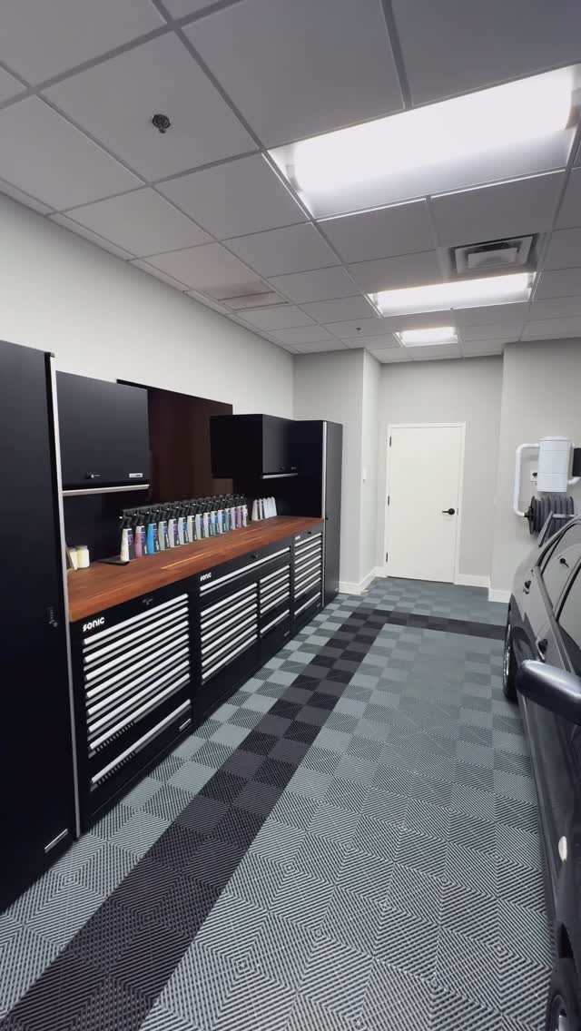 Garage Tool Setup: 8 Ideas That Actually Save Space and Time 5 Black metal tool cabinets with a wooden countertop arranged along a grey tiled workshop floor.