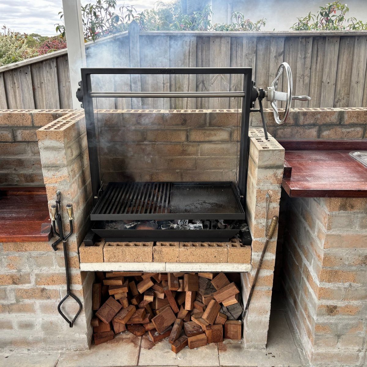 14 Outdoor Built In Grill Ideas for Every Backyard Style 3 A brick outdoor grill station with smoke rising from the black metal cooking grate.