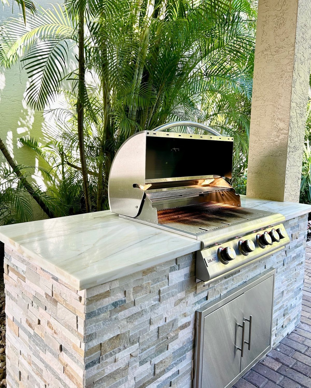 14 Outdoor Built In Grill Ideas for Every Backyard Style 11 Stainless steel built-in grill with an open lid on a stone outdoor kitchen island.