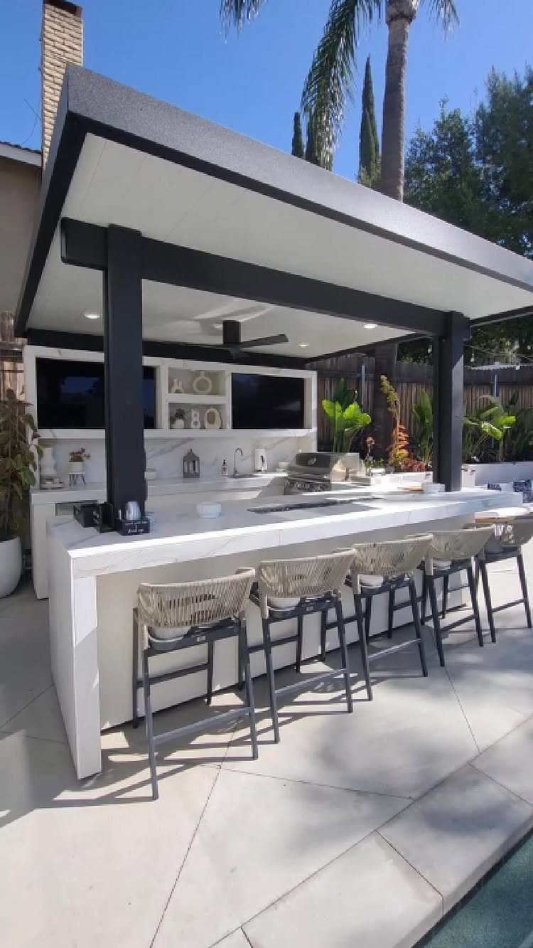 14 Outdoor Built In Grill Ideas for Every Backyard Style 1 Modern white outdoor kitchen station with built-in grill and bar seating under a dark canopy.