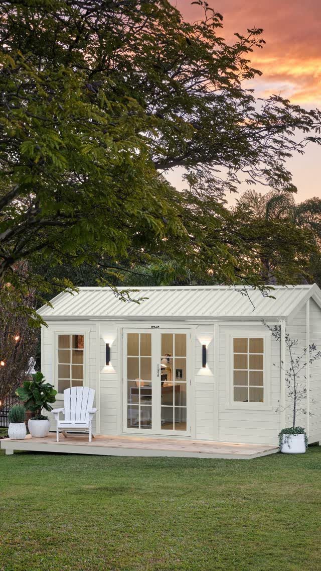 6 Painted Shed Colors for a Backyard That Actually Looks Planned 2 White wooden garden shed with glass doors and windows situated on a wooden deck in a garden.