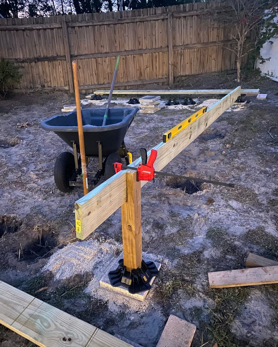 Raised Deck Frame: 8 Ideas From Wood Joists to Galvanized Steel 7 Wooden deck frame construction featuring a level and clamp on a post in a backyard.