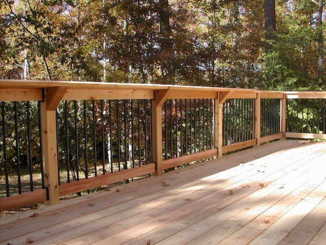 Raised Deck Frame: 8 Ideas From Wood Joists to Galvanized Steel 5 Wooden deck railing with black metal balusters overlooking a forest of autumn trees.