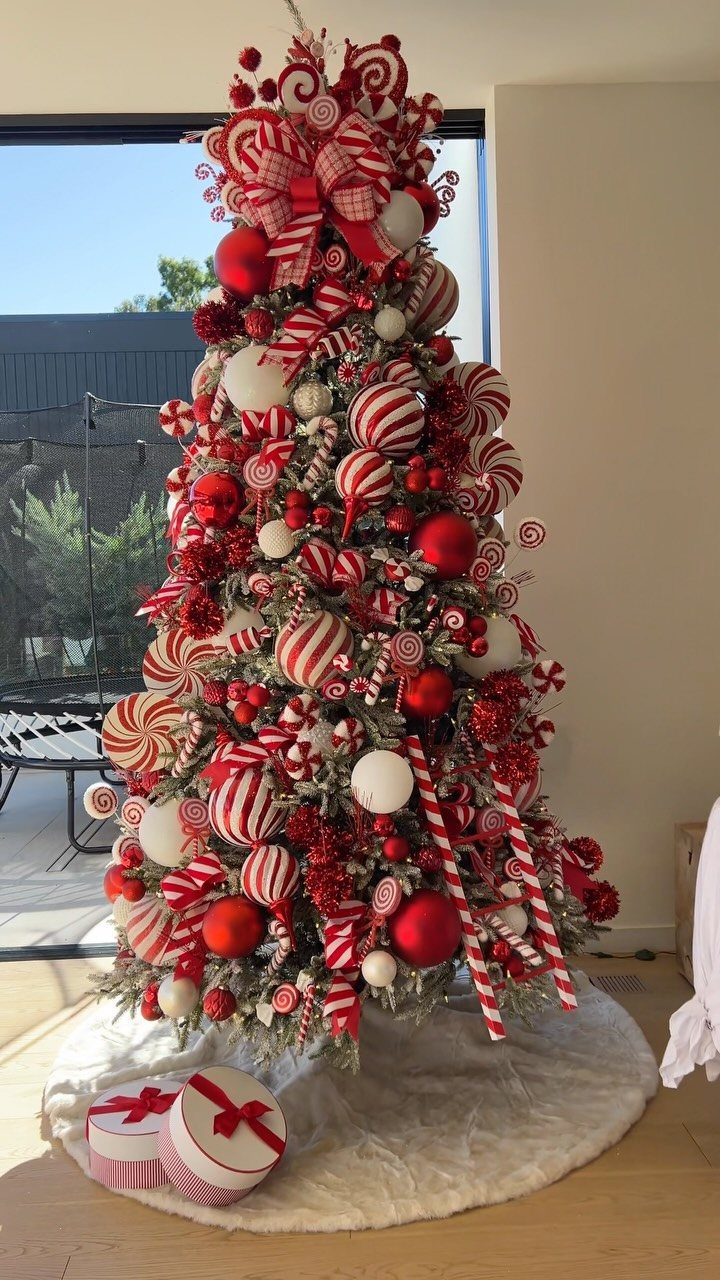 Christmas tree decorated with red and white candy cane ornaments and large red bows.