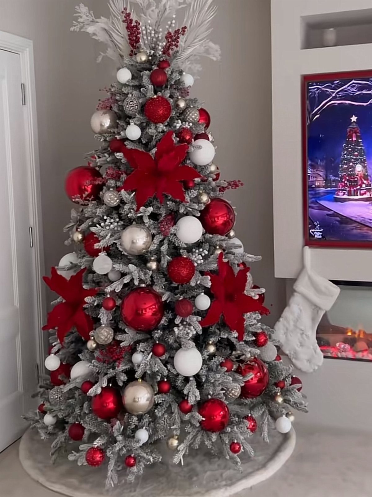 Frosted Christmas tree decorated with red poinsettia flowers, red ornaments, and white baubles.