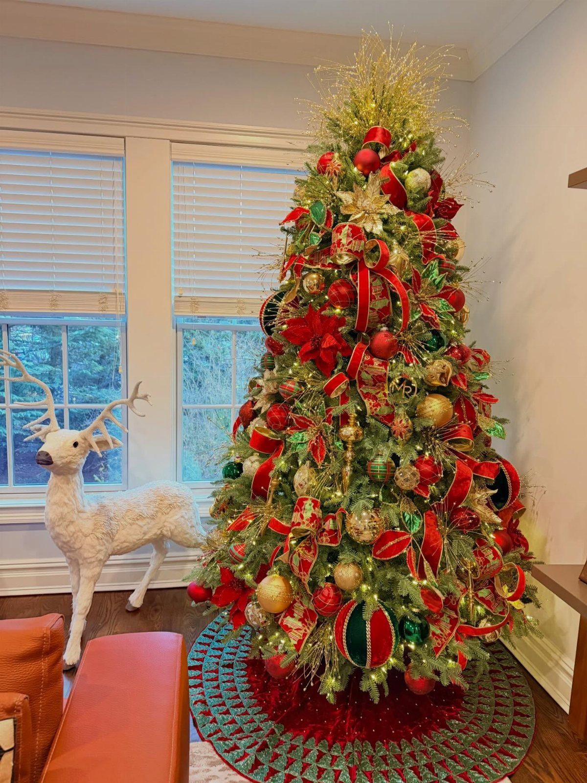 A decorated Christmas tree with red bows, gold flowers, and various red and gold ornaments.